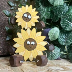 Small sunflower sat on top of a bigger sunflower. made from walnut and painted with a face and arms and legs