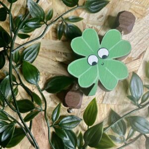Four leaf clover made out of walnut. Painted green with eyes, a smile and walnut block arms