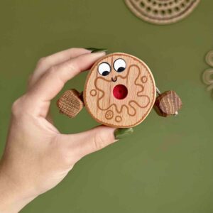 Hand holding a wooden Jammy Dodger toy with red jam centre and smiley face, eco-friendly handcrafted toy.
