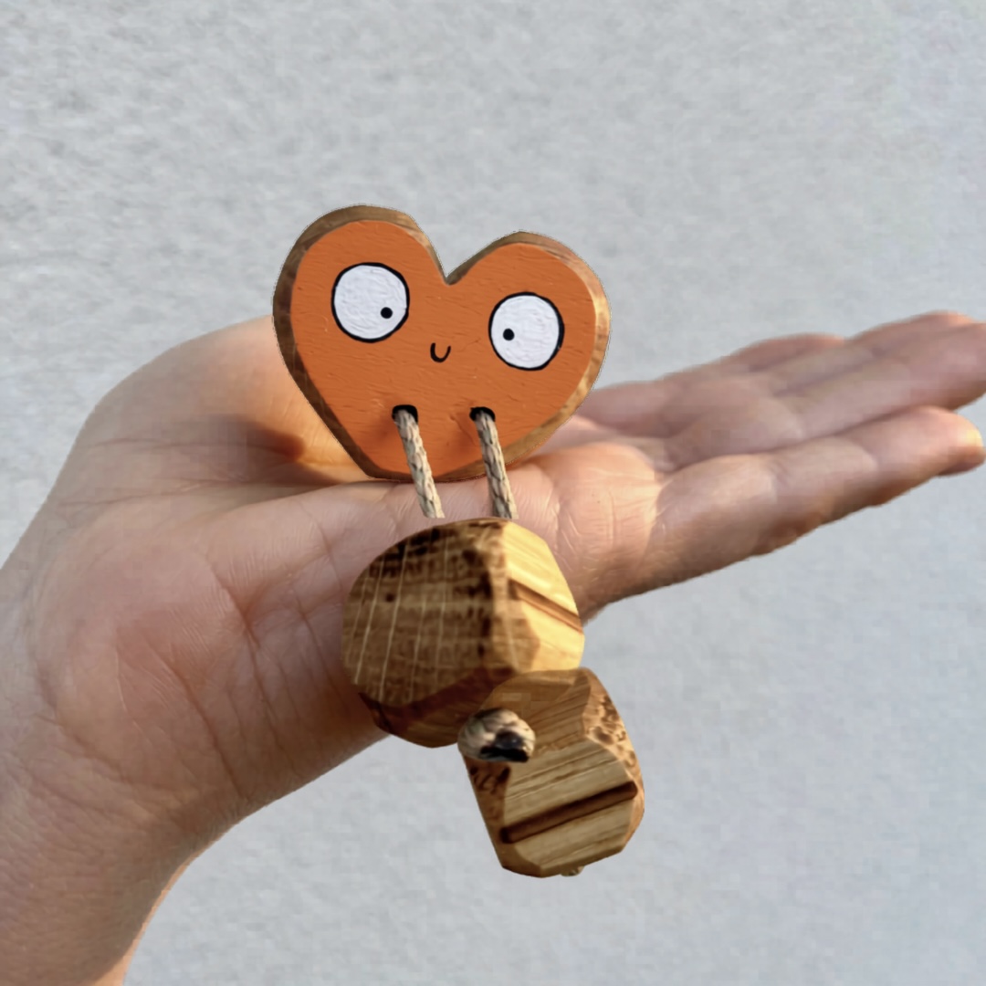 Handmade rainbow wooden heart toy in orange held in hand, open ended wooden toy, eco friendly UK